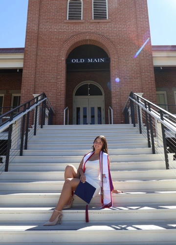 Student sitting on the front steps of Old Main