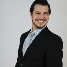 Man in black suit and tie against a white background